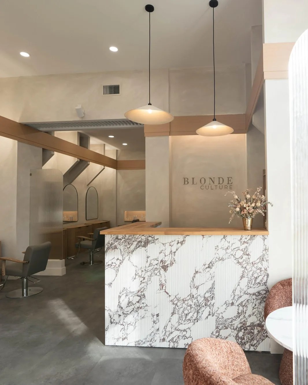 Inside Blonde Culture Winnipeg: marble front desk, styling stations and arched mirrors